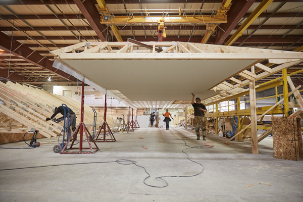 Workers in a factory preparing different parts of roof structures