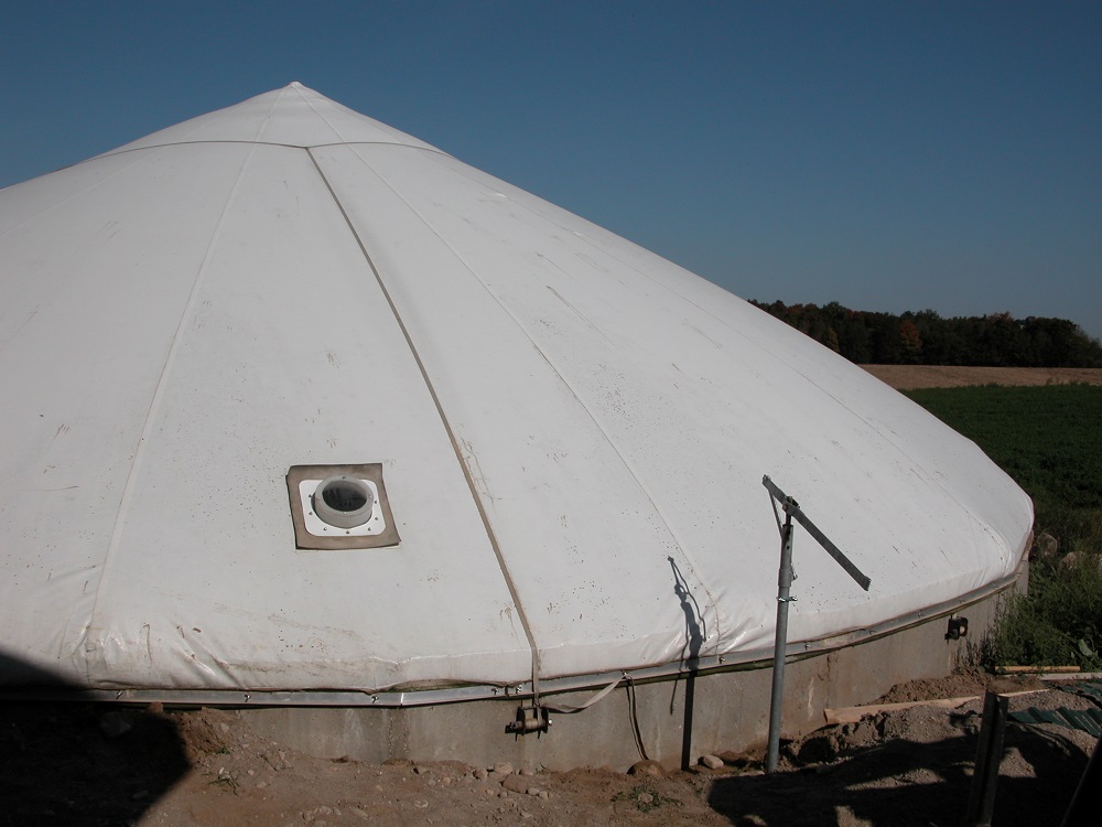 Réservoir circulaire de stockage de fumier en béton avec une couverture souple imperméable gonflée sous pression.