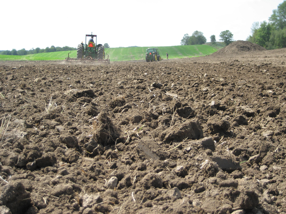 Tractors tilling up and down on a sloped field