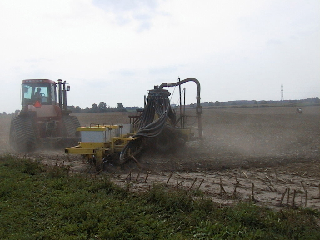 A tractor pulling a drag hose which applies liquid manure in a field