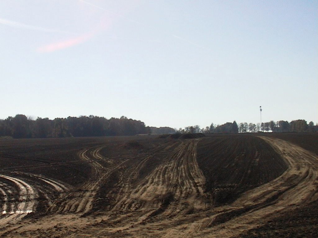 A plowed field that shows wet tire tracks from repeated applications of manure