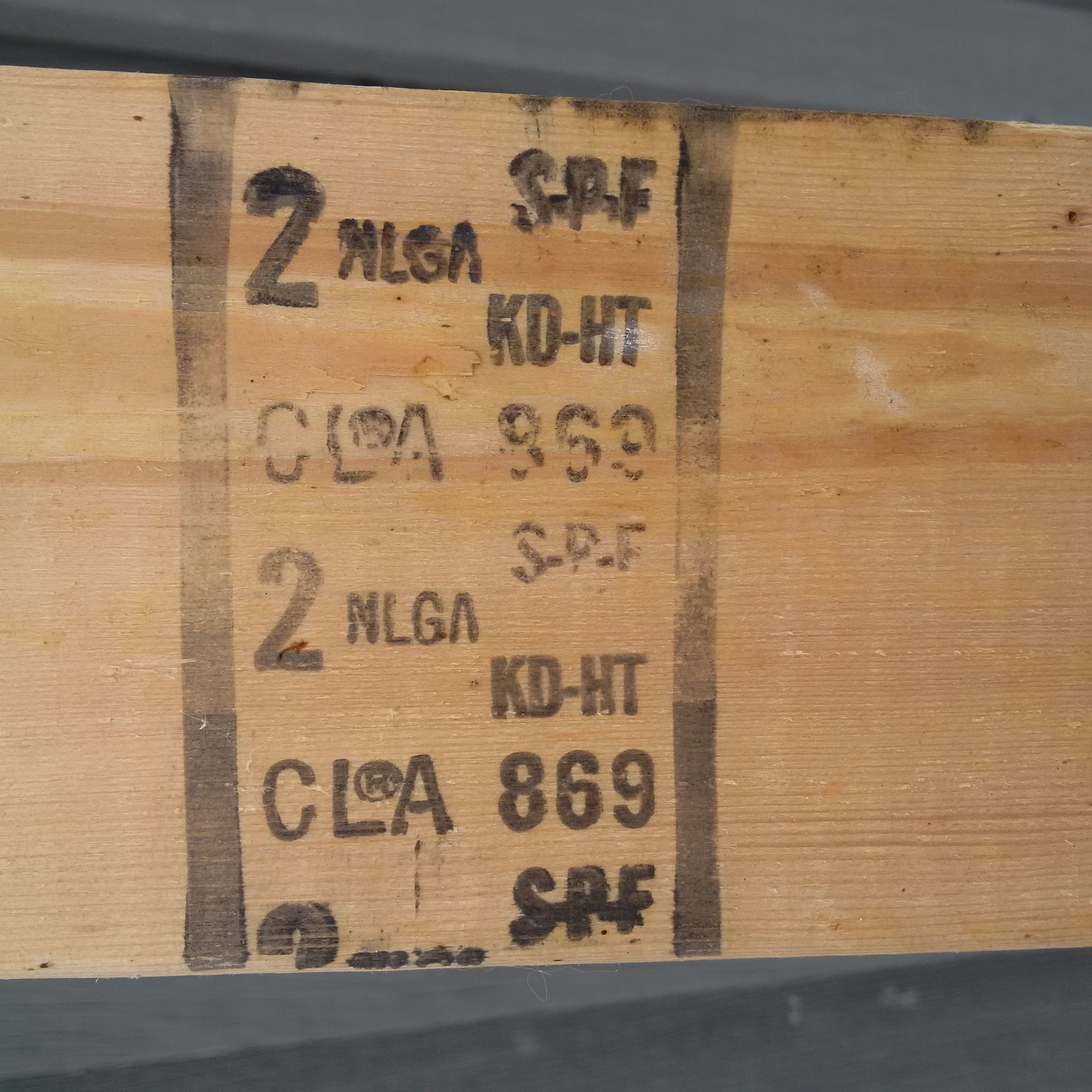 Cette figure montre un exemple d’estampillage sur du bois. Ces sciages ont été classés conformément aux règles de classement de la NLGA par l’'Association canadienne de l’'industrie du bois et il a été produit par la scierie numéro 869. Ce bois d’'œuvre est constitué d’'épinette-sapin-pin, il a été séché au séchoir, traité à la chaleur et s’'est vu attribuer une classe 2.