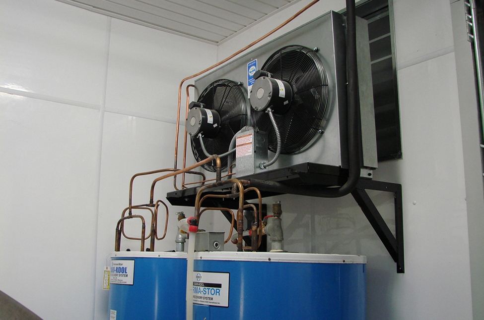 Two fans above two large blue tanks connected by piping