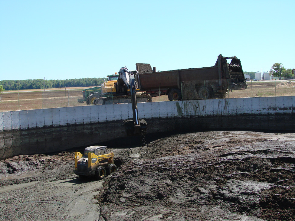 Skid steer and high hoe used to remove sediment from sand-laden manure storage