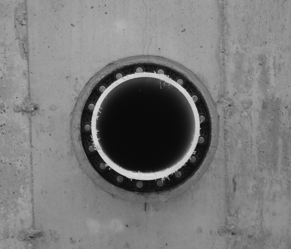 Une photo montrant un joint d’étanchéité modulaire de forme circulaire entre le tuyau et l’ouverture pratiquée dans le mur de béton, lequel prévient les fuites à l’ouverture.