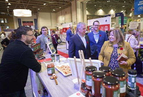 A group of people standing around a booth with samples out front. Minister Lisa Thompson, Joe Fusco, Senior Vice President, Metro and Mathieu Robitaille, Head of Marketing, Metro Ontario Inc. Jack Sullivan from OMAFRA and David Bruno from Donato’s Bakery.