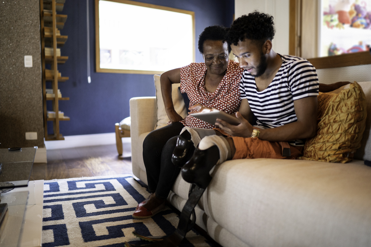 Son using digital tablet with his mother