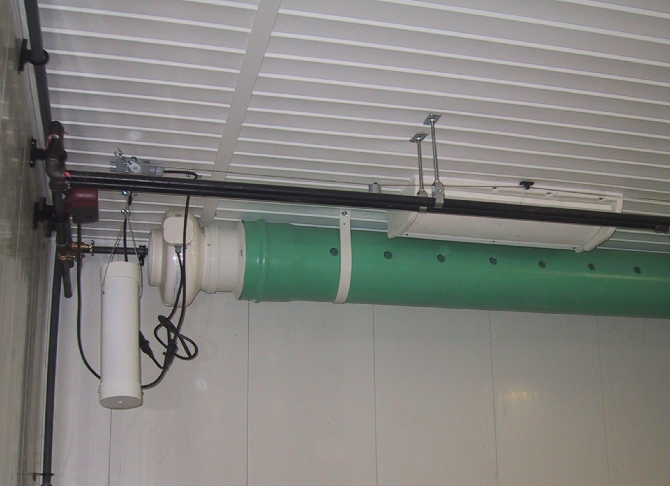 A rigid duct (mounted at ceiling height) with a fan on the left end and air distribution holes, along the duct, to assist in air circulation