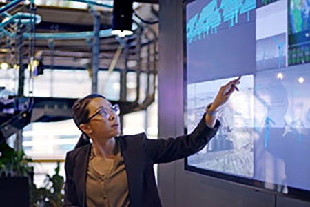 Image of a woman presenting data on a screen