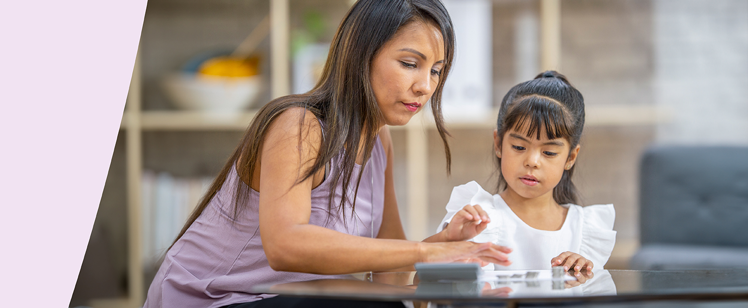 An early childhood educator and a young child playing with toy coins and a calculator.