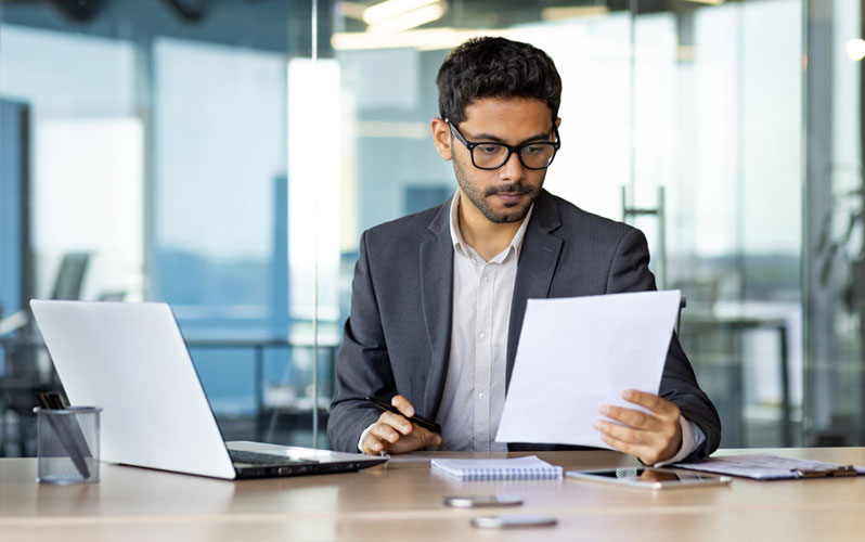 Man in a suit looking over a piece of paper in an office environment