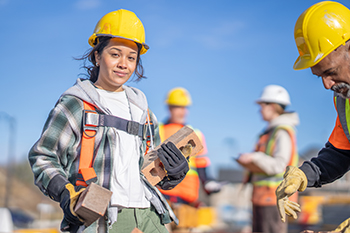 A young student wearing protective equipment in a construction site.