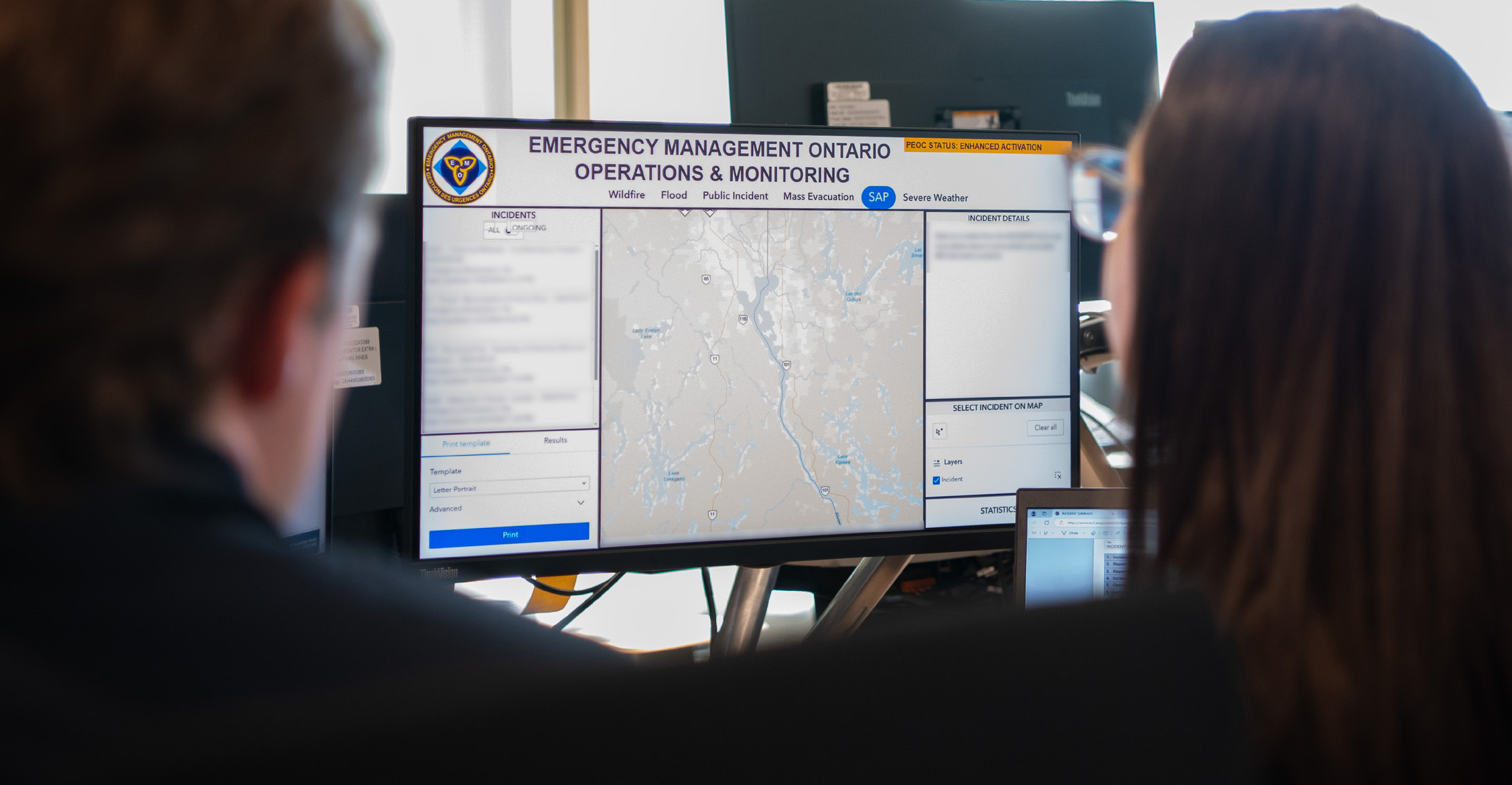 Two people sitting in front of an Emergency management Ontario screen.