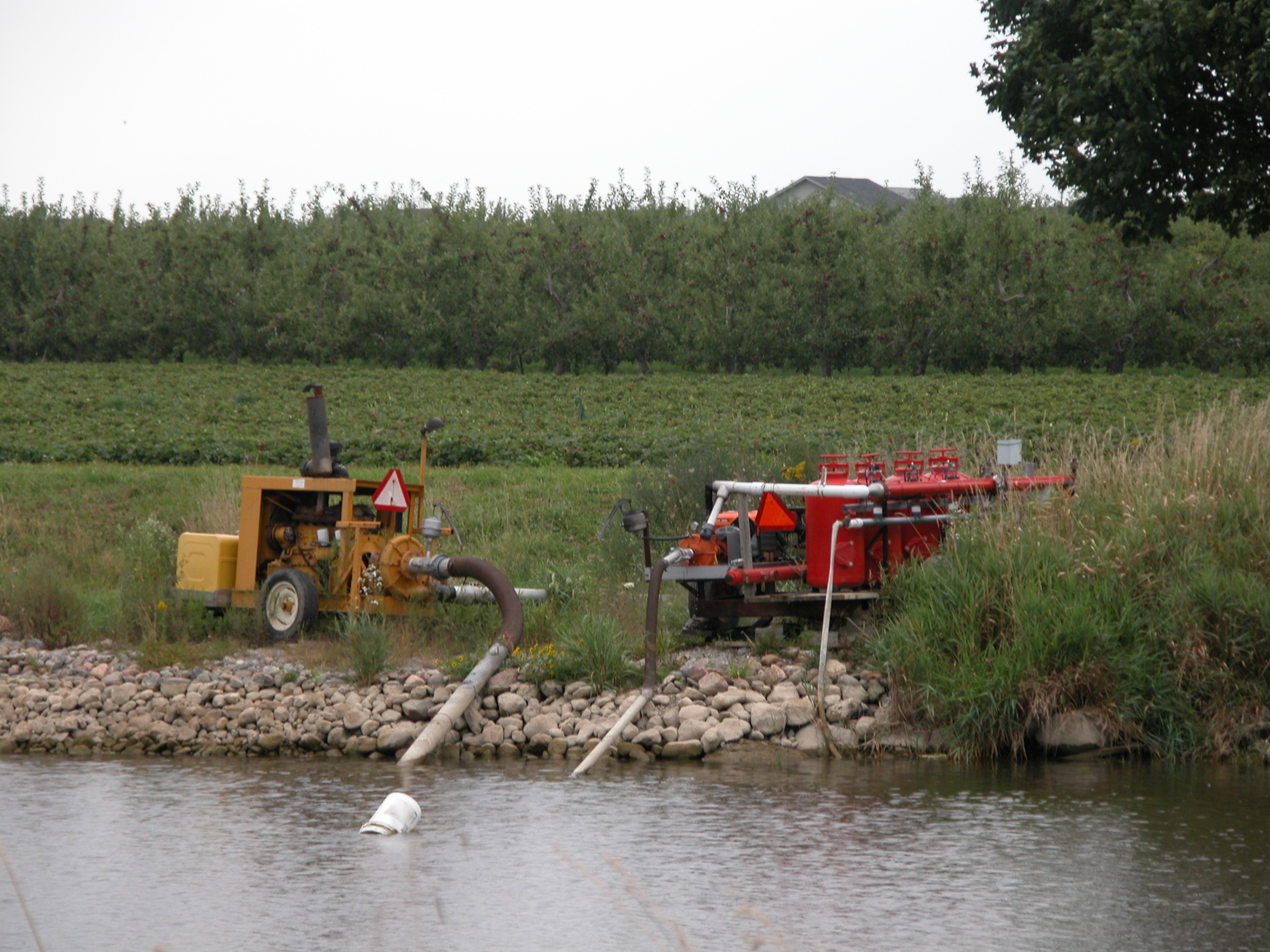 2 mobile pumps at a water source with their hoses going into the water.