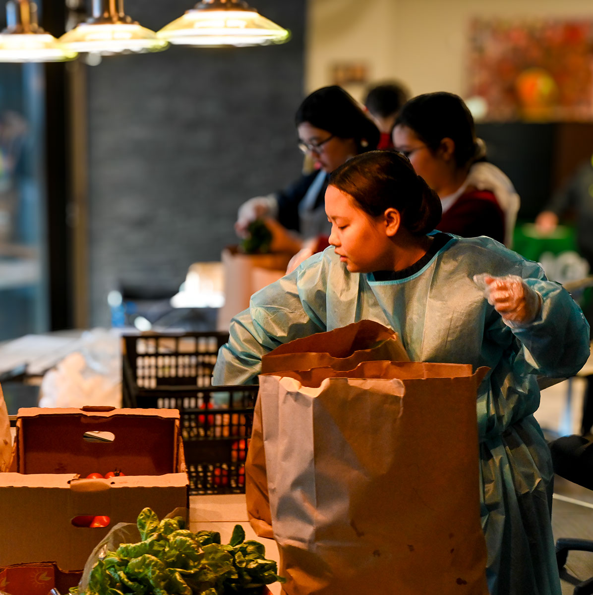 An image of several people filling brown paper bags with fresh produce for the Good Green Food Reclamation program.