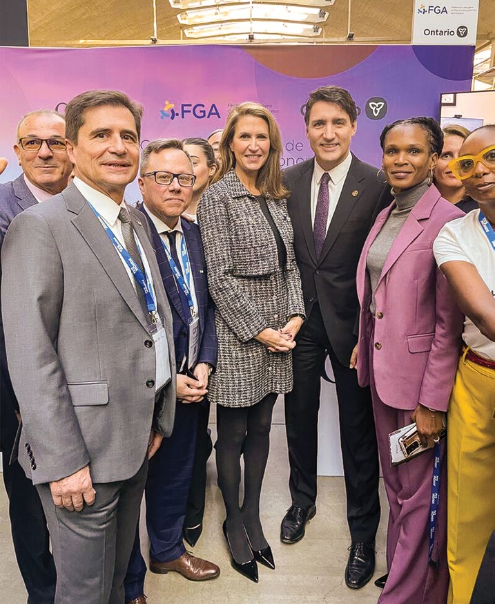 Photograph of The Right Honourable Justin Trudeau, Prime Minister of Canada, and The Honourable Caroline Mulroney, Ontario Minister of Francophone Affairs, surrounded by several key members of the Ontario community, standing in front of the FrancoTech FGA booth.