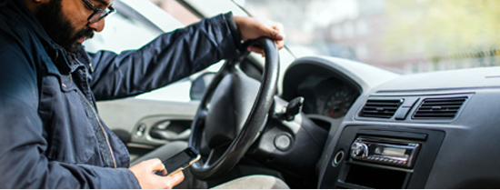 Photo of a driver looking down at their phone.