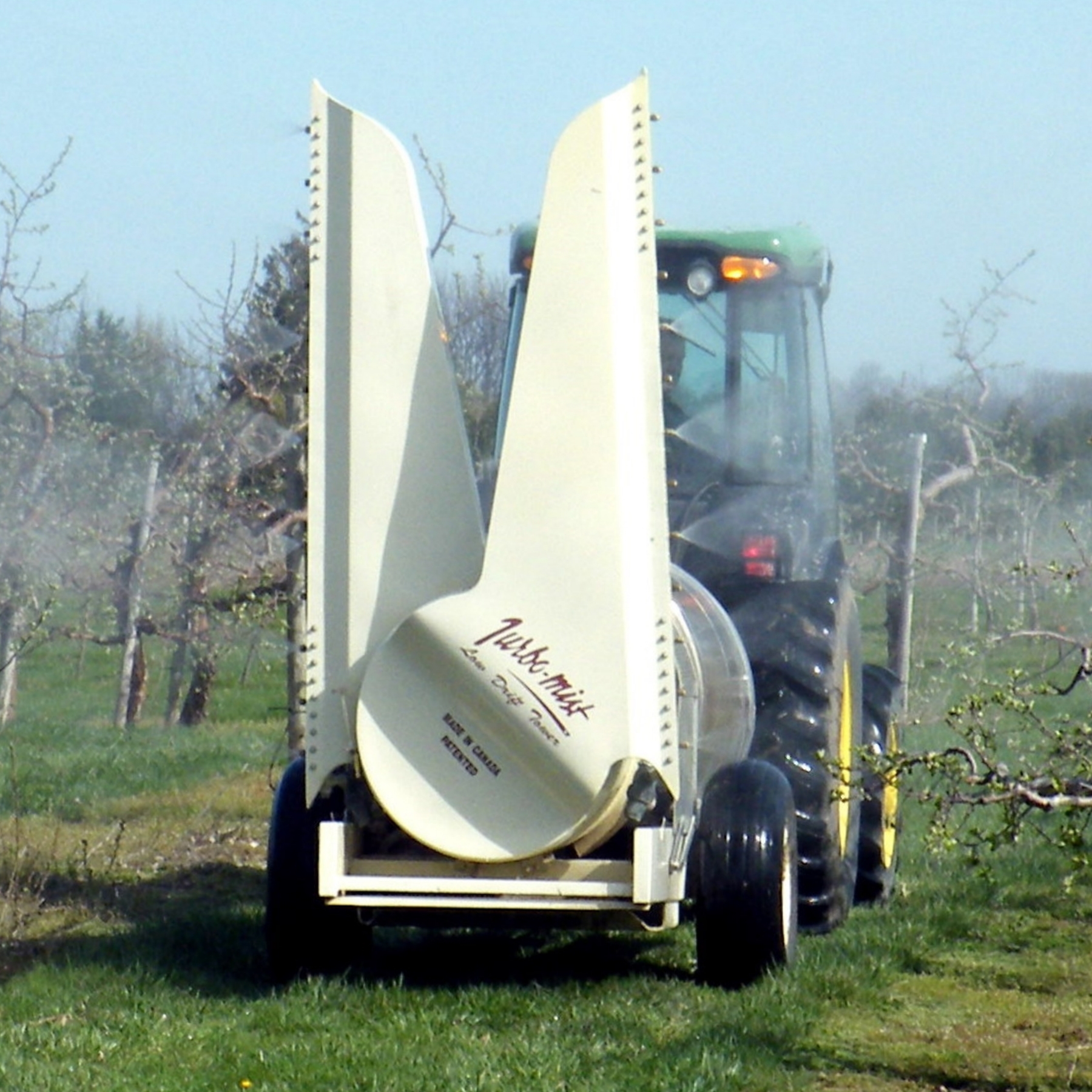 A tower airblast sprayer being pulled behind a tractor.