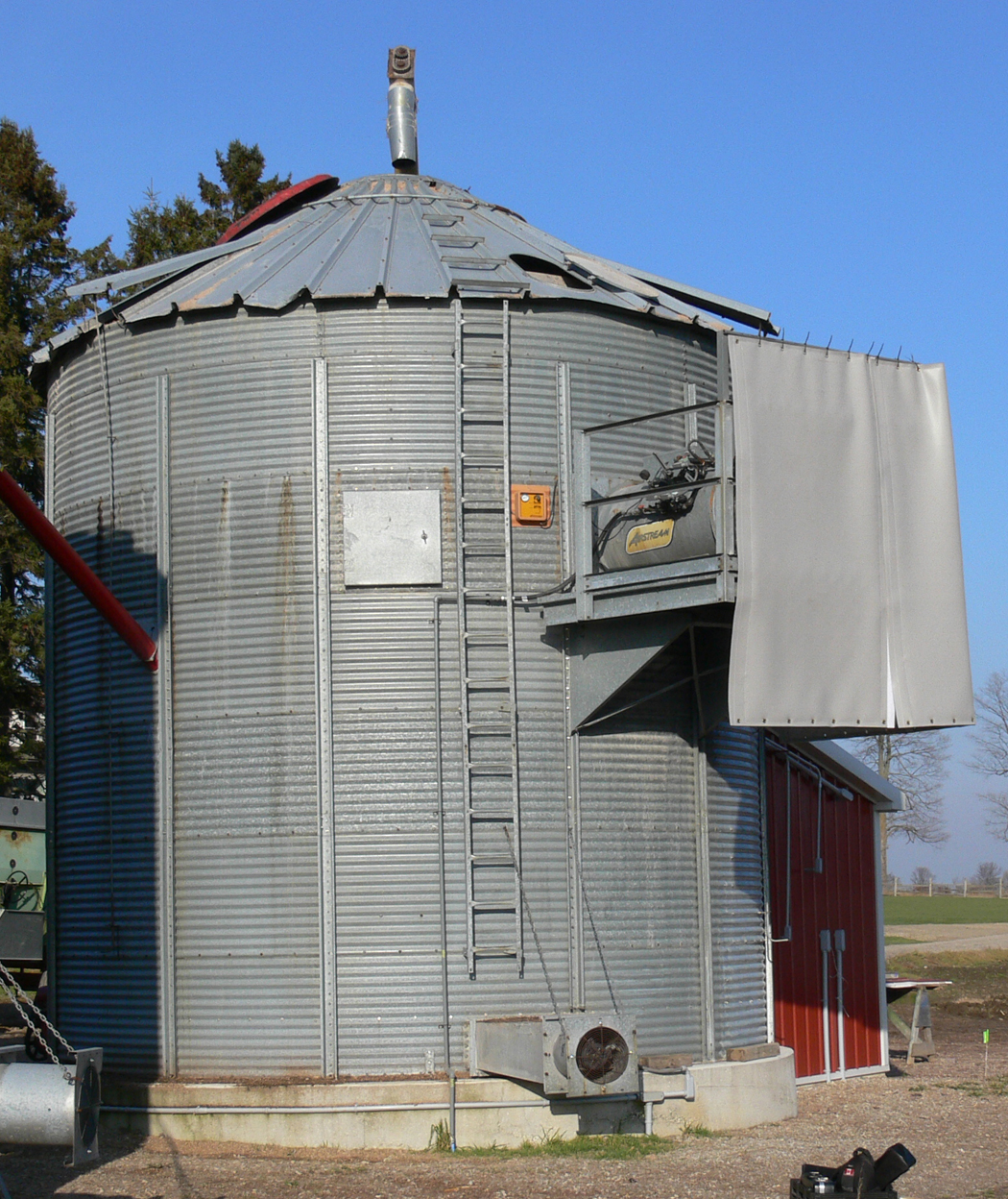 une couverture acoustique suspendue devant un séchoir situé à côté d’une cellule à céréales